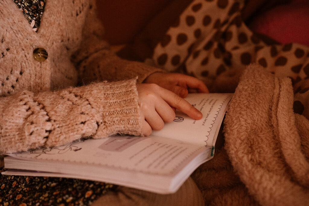 Meisje leest uit de Zoete Zusjes en gebruikt haar vinger om de tekst goed te kunnen lezen. 