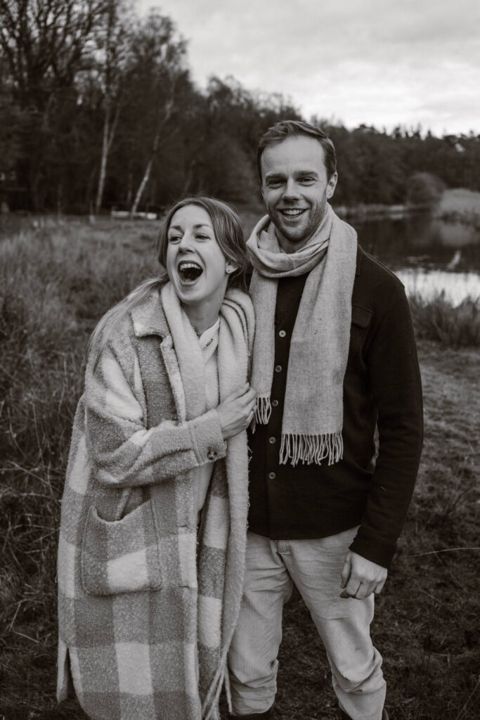 Broer en zus staan naast elkaar bij de rivier de Regge in Ommen, terwijl ze lachen met elkaar om een grappig verhaal dat hij vertelt. 