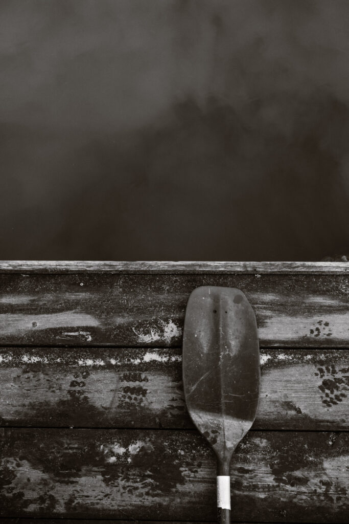 Zwart wit foto van een peddel op een vlot dat op het water drijft